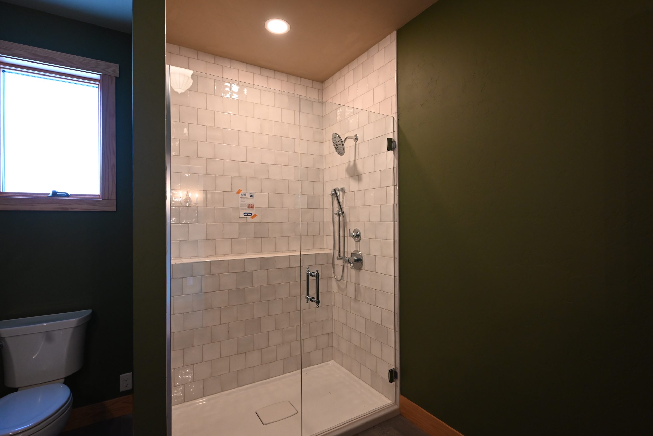 Tiled walk-in shower with glass panel by Bartow Builders